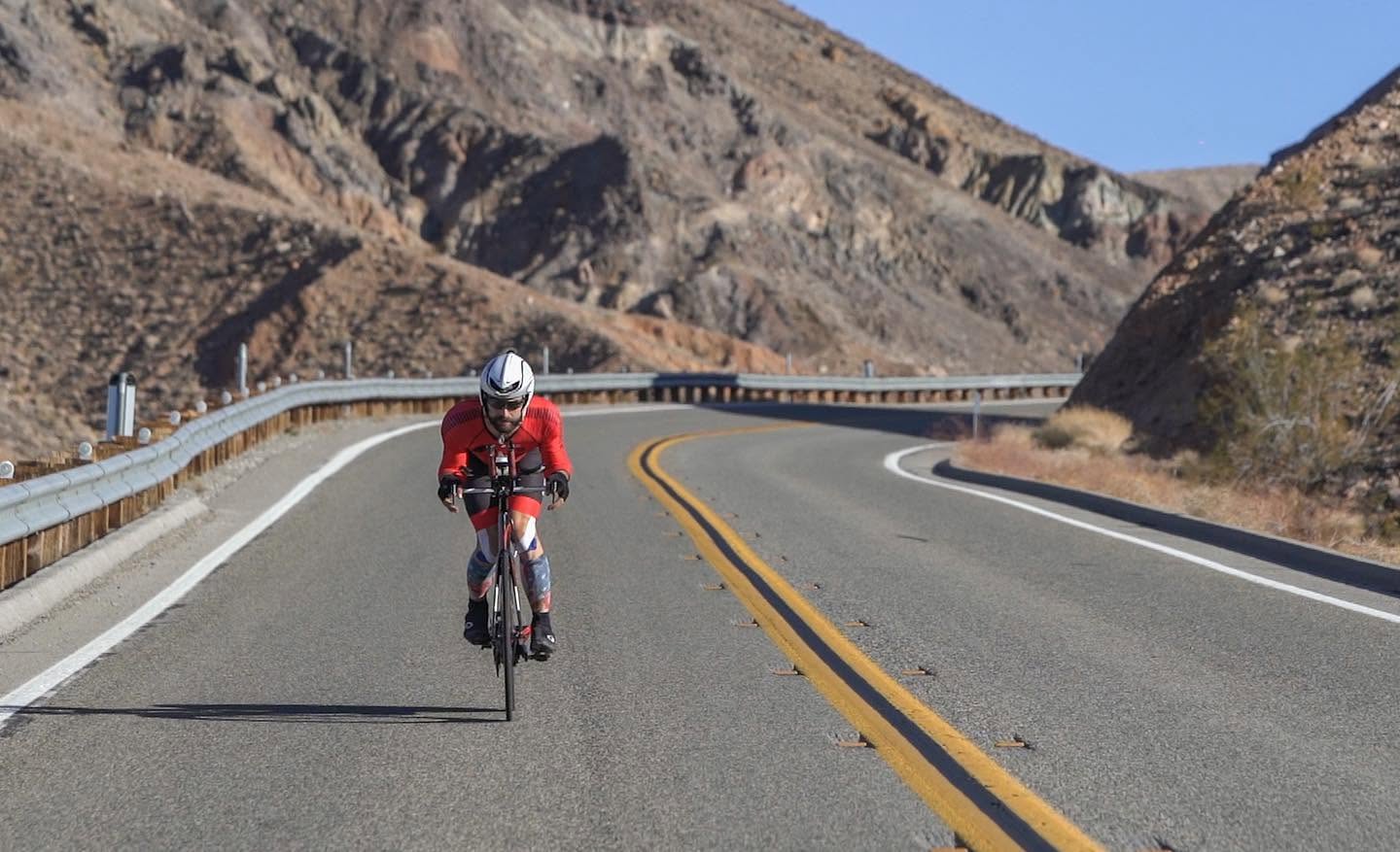 Ryan Tetz rides a time-trial bicycle through a desert highway bend