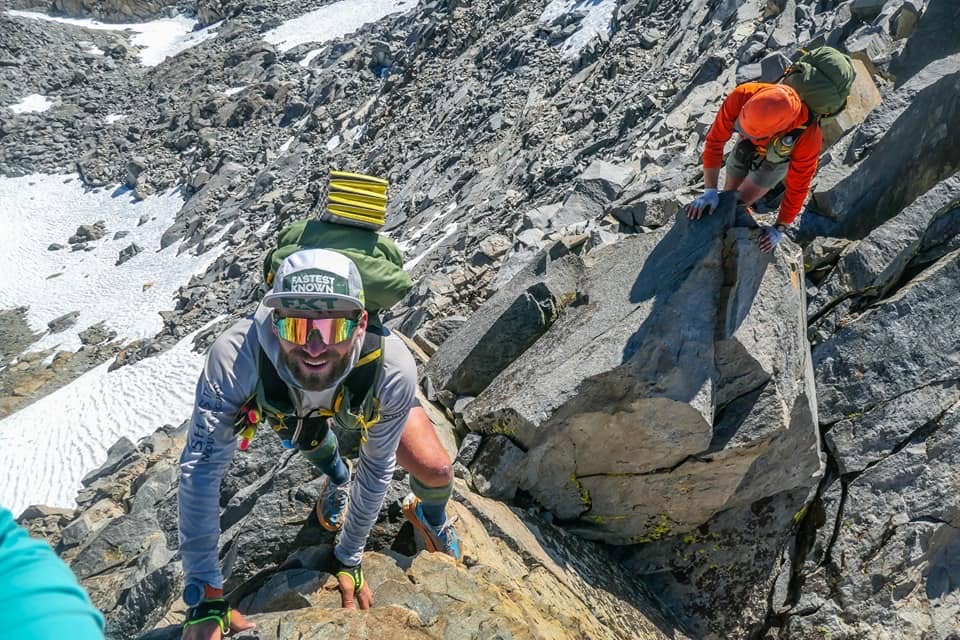 Three athletes move through steep blocky terrain during Convoluted Bliss