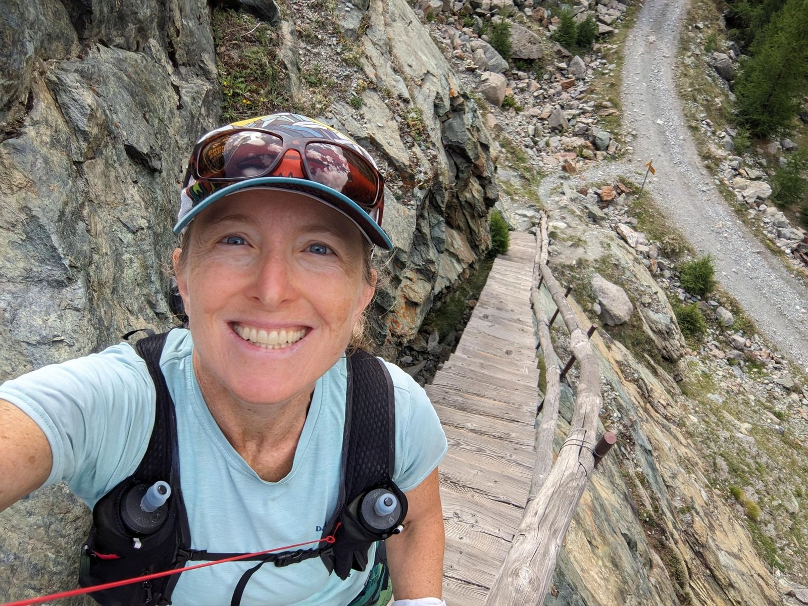 Renee Elsdon Jacobs smiles beside a wooden bridge in mountain terrain