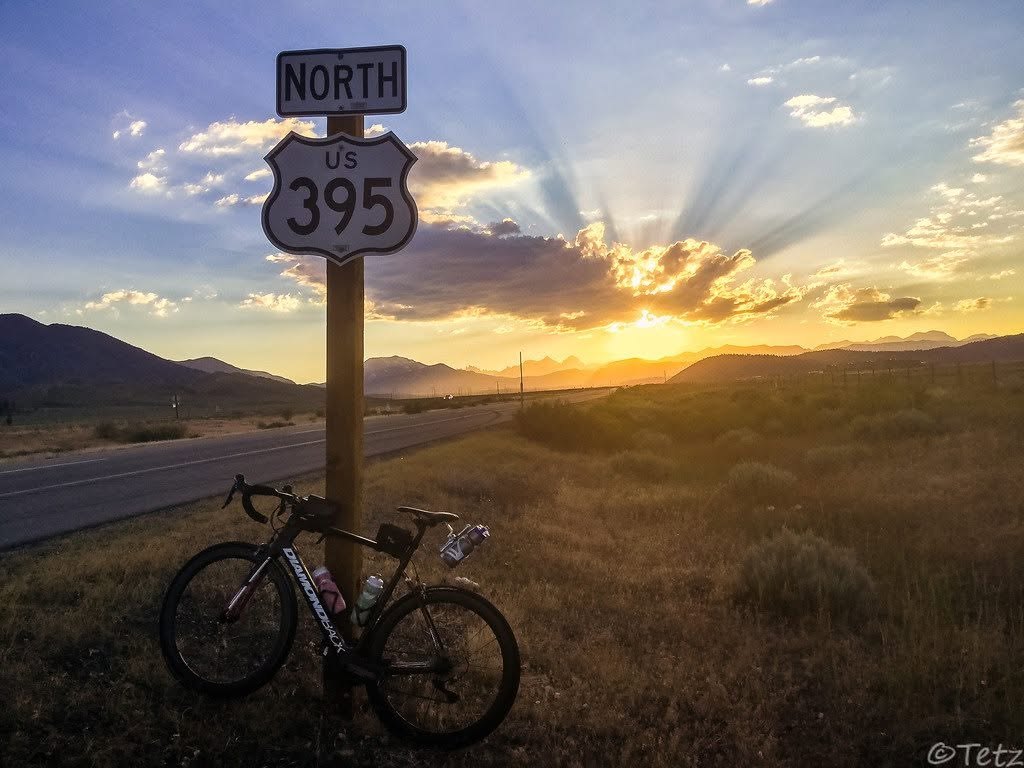 A road bicycle rests beneath a U.S. 395 North sign in low light beside the Sierra