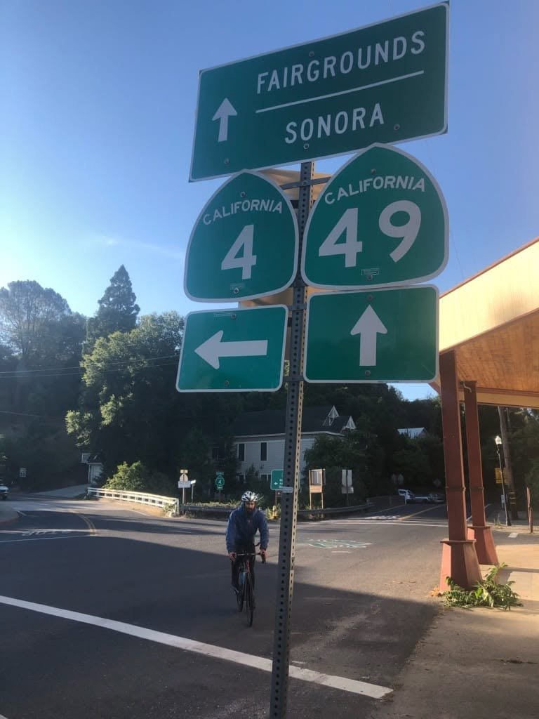 Ryan Tetz rides beneath California Routes 4 and 49 signs at the end of the 2019 Triple Sierra Crossing in Angels Camp