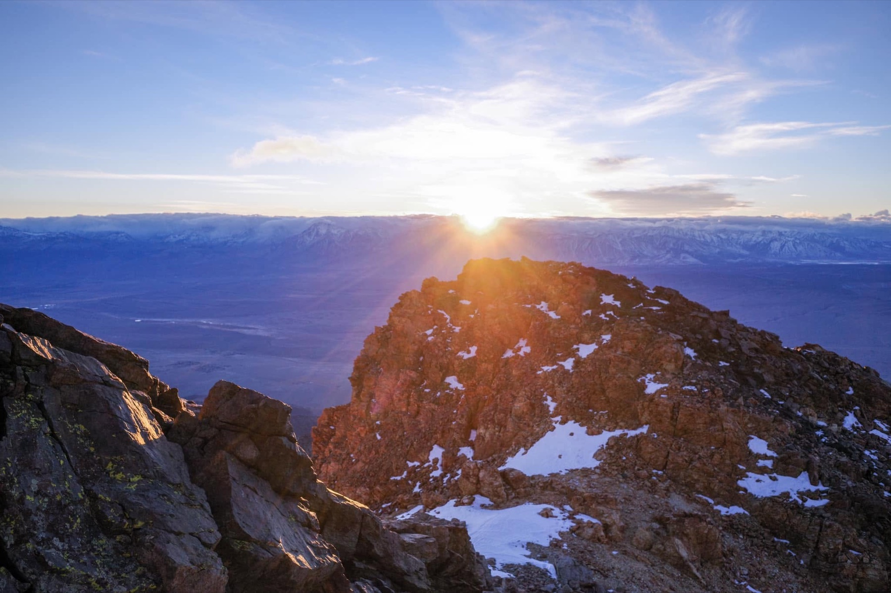 The sun rises across Owens Valley from a rocky White Mountains summit ridge