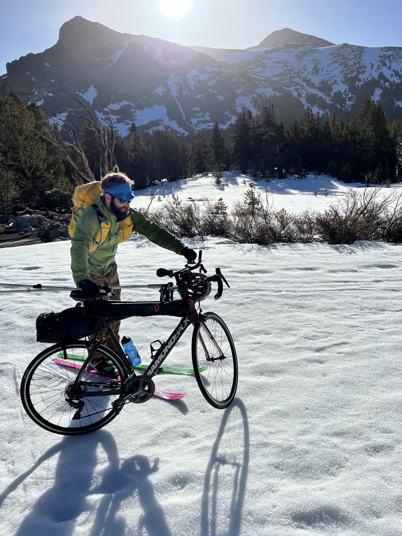 Ryan Tetz stands with a bicycle and skis on snow during the 2022 Yosemite Winter Picnic